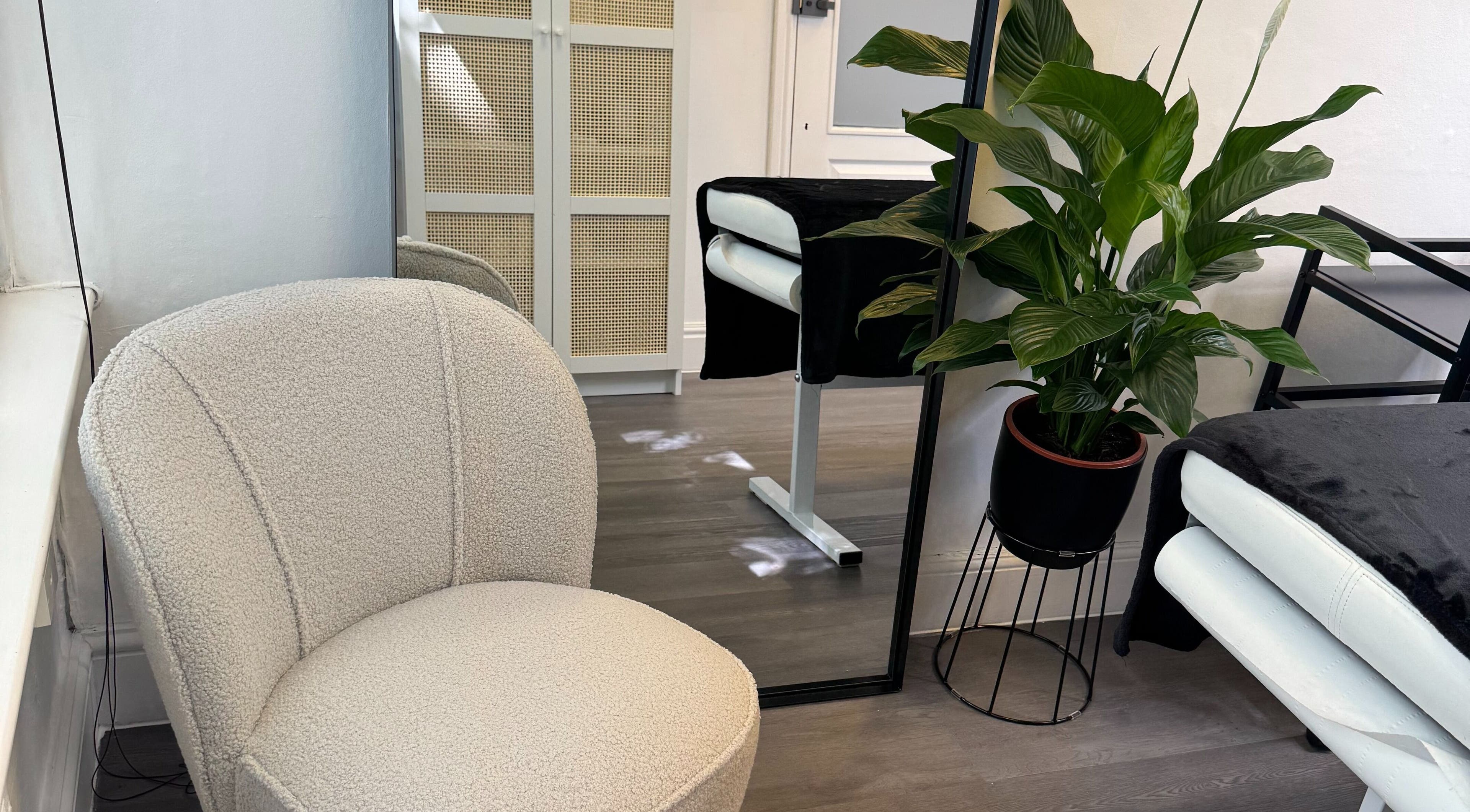 Elegant treatment room at Defined by Linda in Bristol, England, GB with plush chair and lush plant.