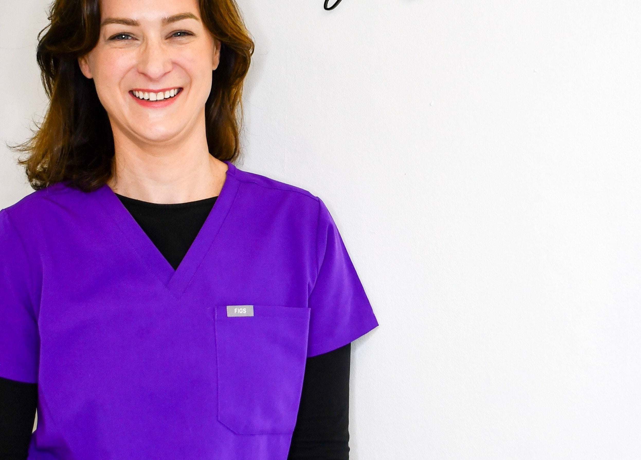 Smiling professional in purple scrubs at Defined by Linda, Bristol, England, GB wellness venue.