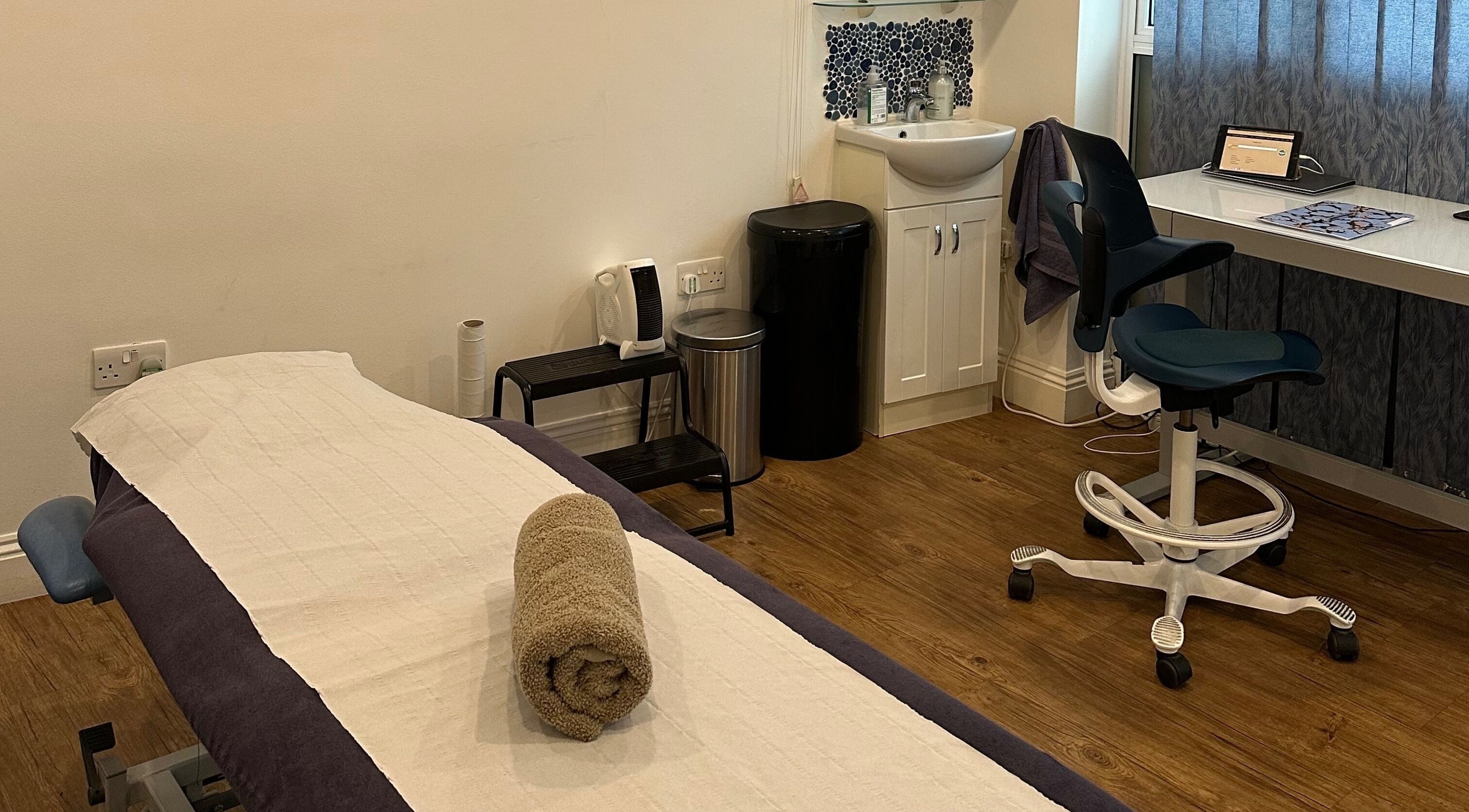 Relaxing treatment room at Elementa, Hauxton, England, GB. Stylish decor with massage bed and cozy chair.