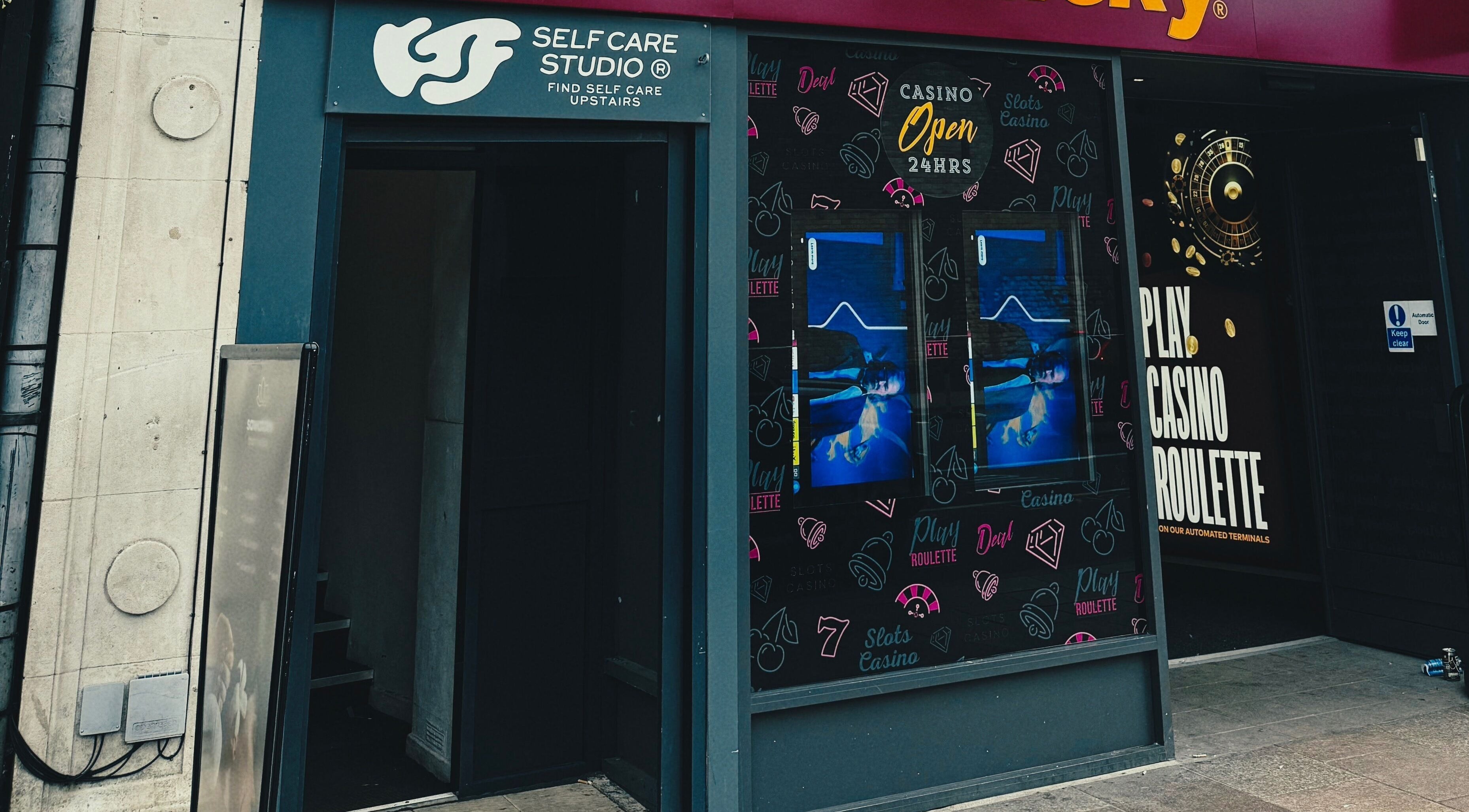 Entrance to KTF Self Care Studio in Cardiff, Wales, GB, welcoming visitors beside a vibrant casino facade.