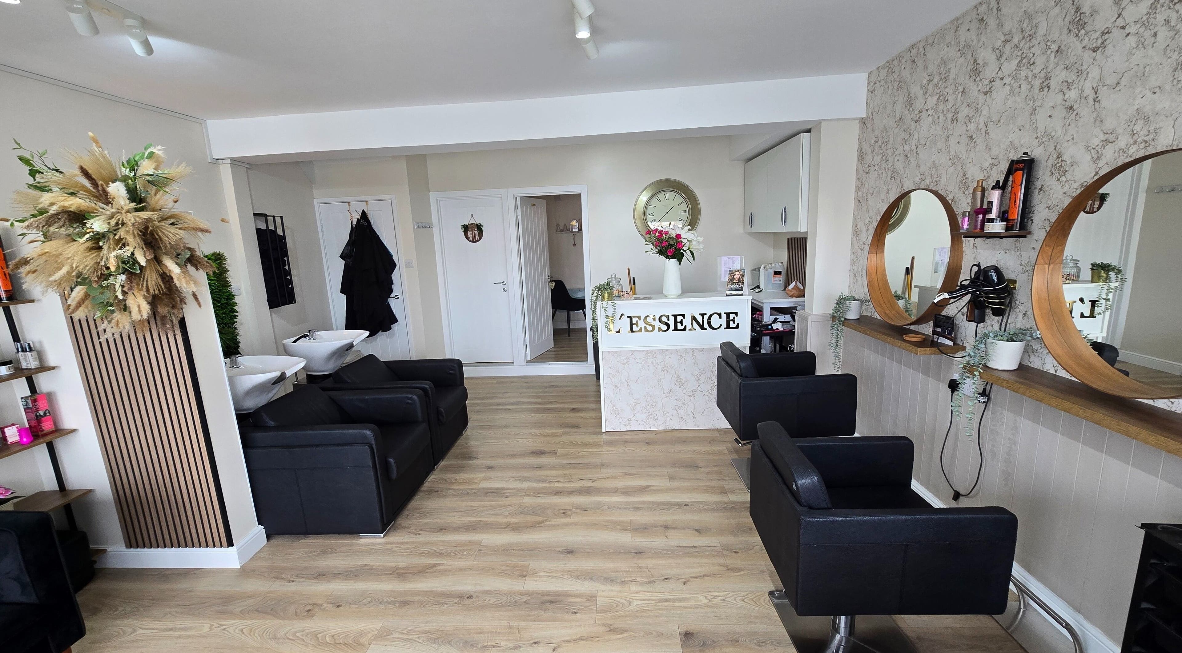 Stylish interior of L'Essence Hair & Beauty in Derby, England, GB, featuring chic salon chairs and mirrors.
