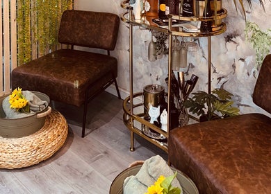 Stylish seating area at Eden Salon, Tyldesley, England, GB with plush chairs and a decorative bar cart.