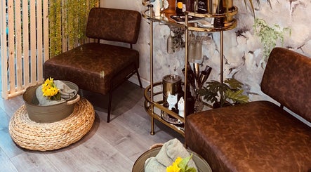 Stylish seating area at Eden Salon, Tyldesley, England, GB with plush chairs and a decorative bar cart.