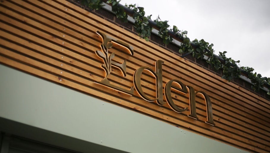 Front signage of Eden Salon, Tyldesley, England, GB with wooden slats and greenery.