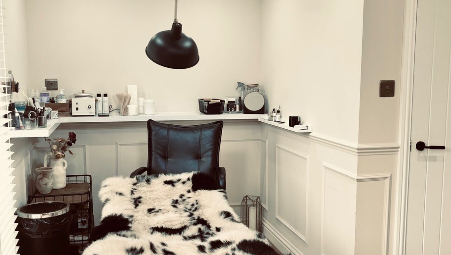 Cozy treatment room at Jasmine’s Beautique in Ebley, England, featuring plush seating and modern decor.