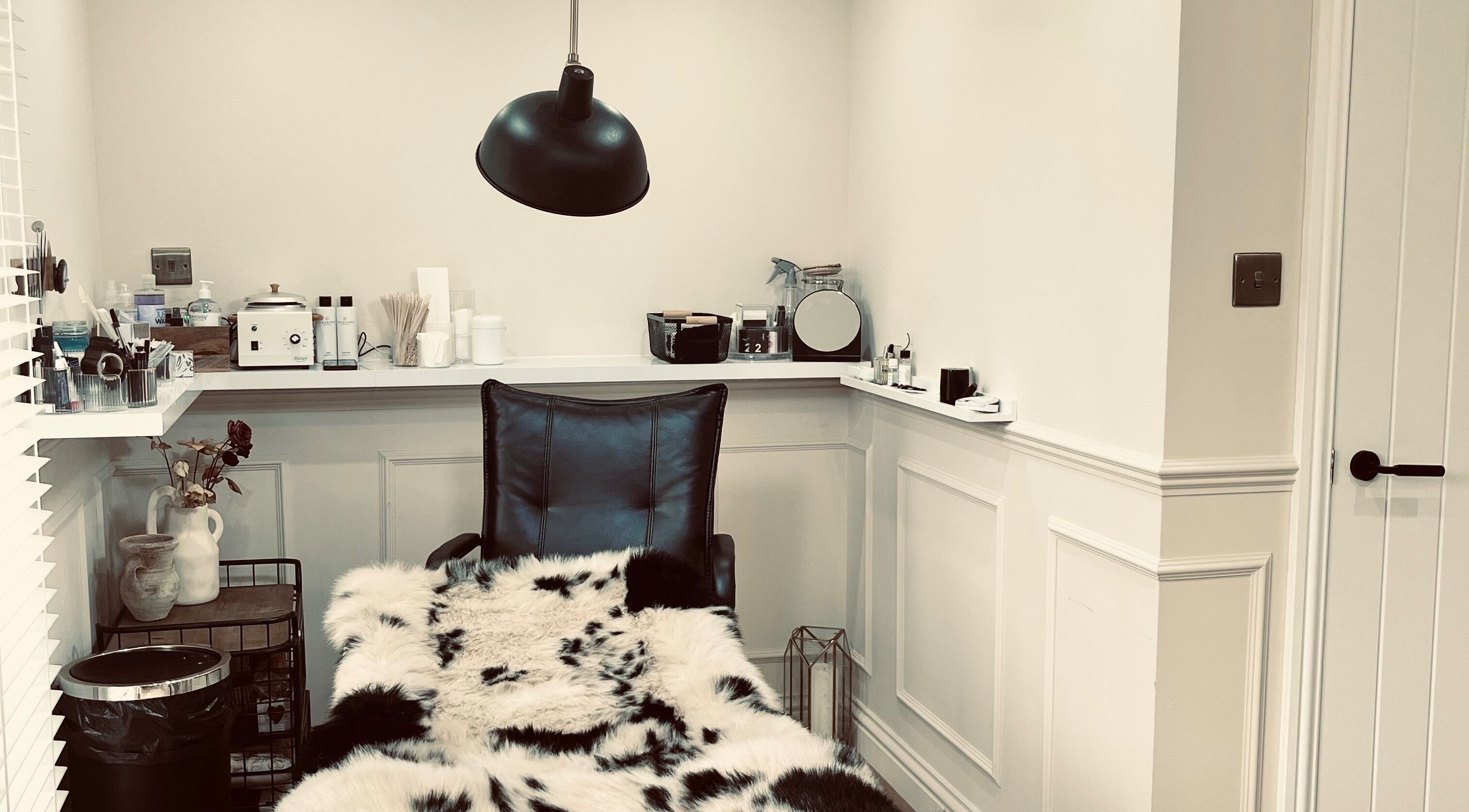 Cozy treatment room at Jasmine’s Beautique in Ebley, England, featuring plush seating and modern decor.