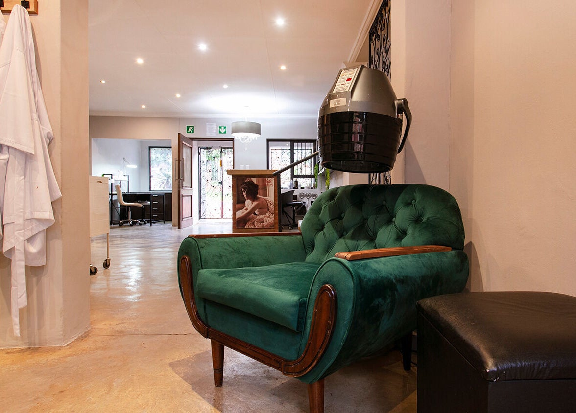 Elegant waiting area at Authentic Collection, Pretoria, Gauteng, ZA with a plush green chair and stylish decor.