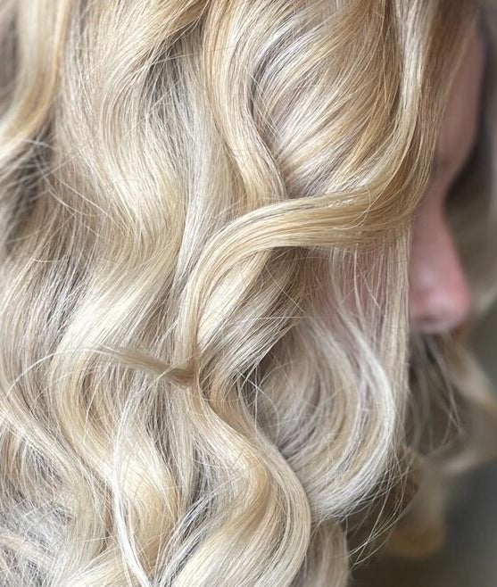 Elegant blonde curls styled at The Salon, Marchwiel, Wales, GB, showcasing vibrant hair artistry.