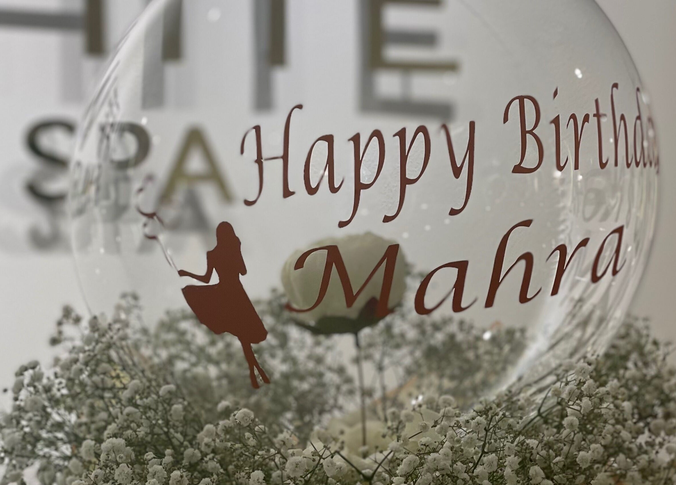 Birthday celebration decor at Off White Salon & Spa, Abu Dhabi, AE showing a personalized balloon with flowers.