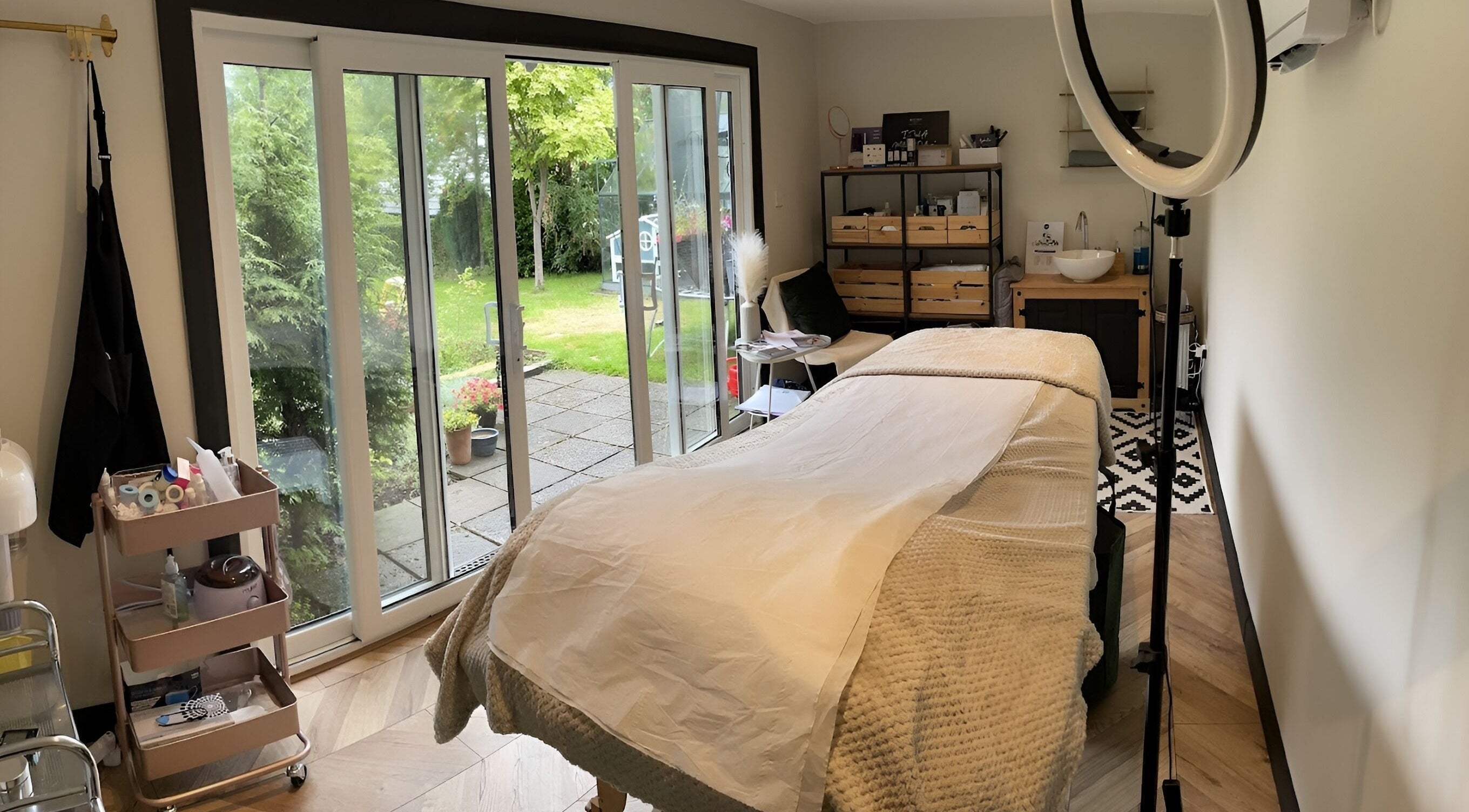 Relaxing treatment room at The Secret Salon, Rugeley, England, GB with cozy bed and serene garden view.