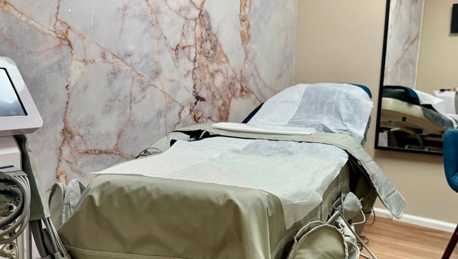 Modern treatment room in Shape Zone London, England, GB with elegant marble wall and comfortable therapy bed.