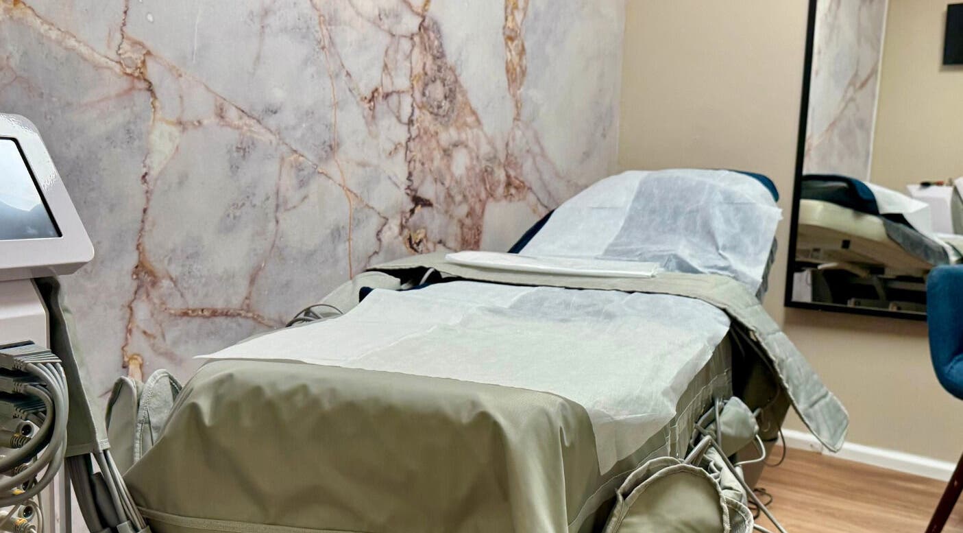 Modern treatment room in Shape Zone London, England, GB with elegant marble wall and comfortable therapy bed.