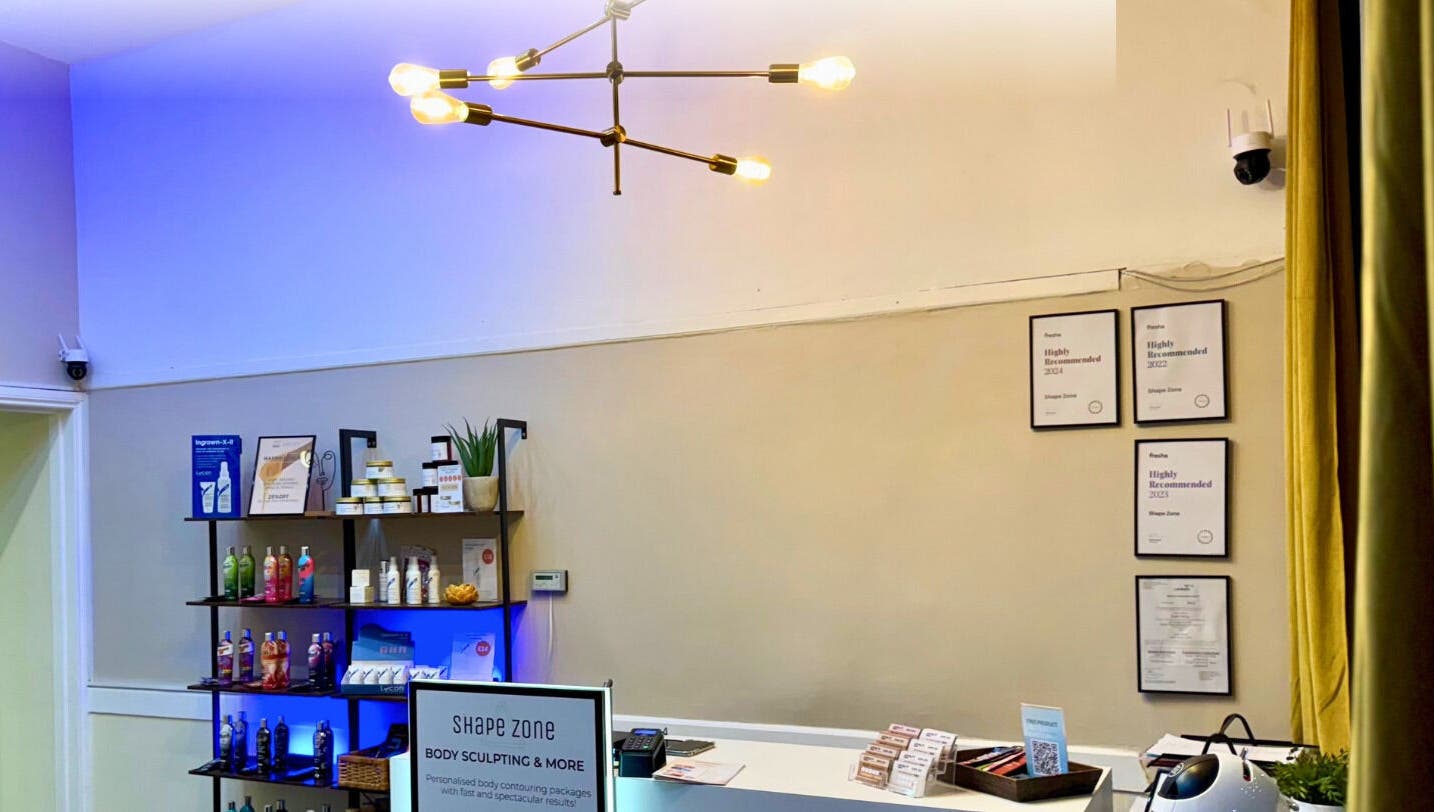 Reception area of Shape Zone London in London, England, GB with stylish lighting and displayed beauty products.
