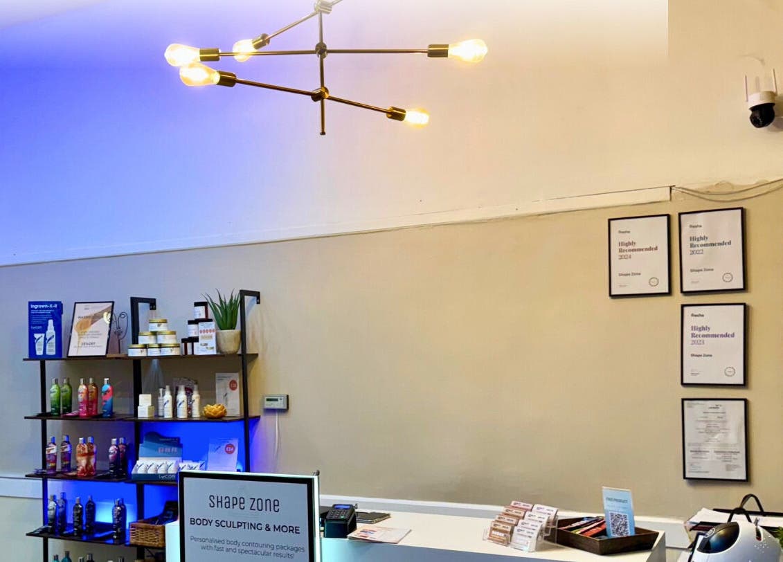 Reception area of Shape Zone London in London, England, GB with stylish lighting and displayed beauty products.