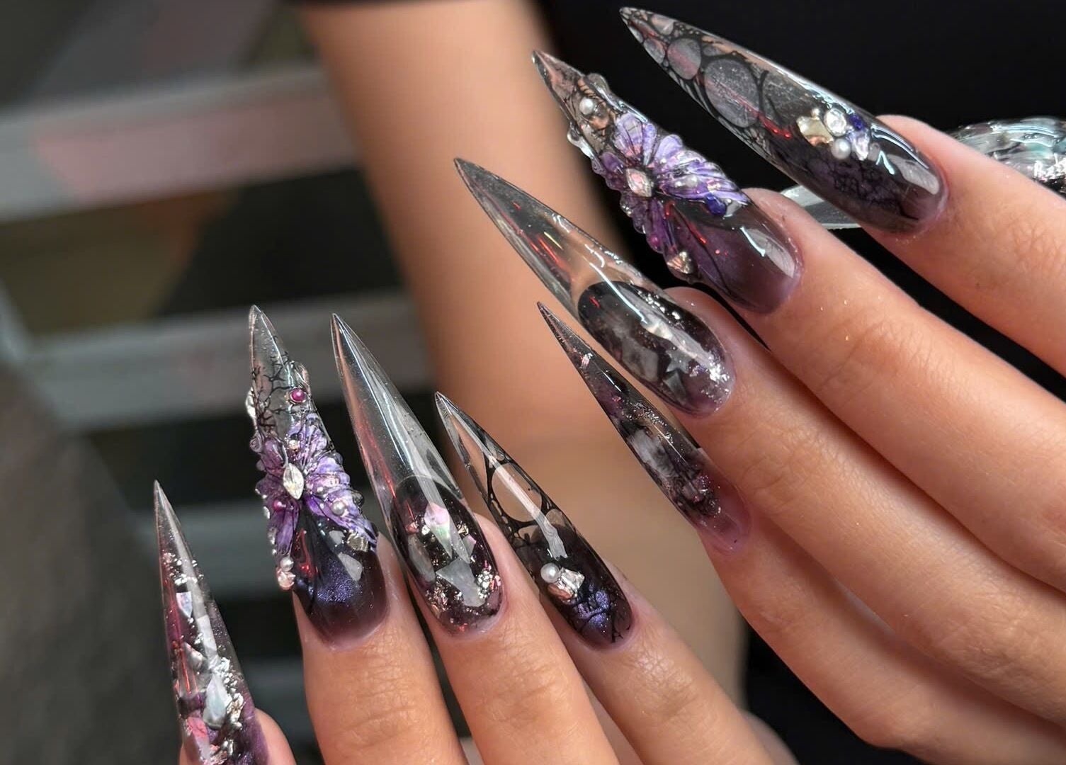 Intricate nail art at Iconic Nails Studio, Los Altos, California, US, showcasing detailed purple 3D designs.