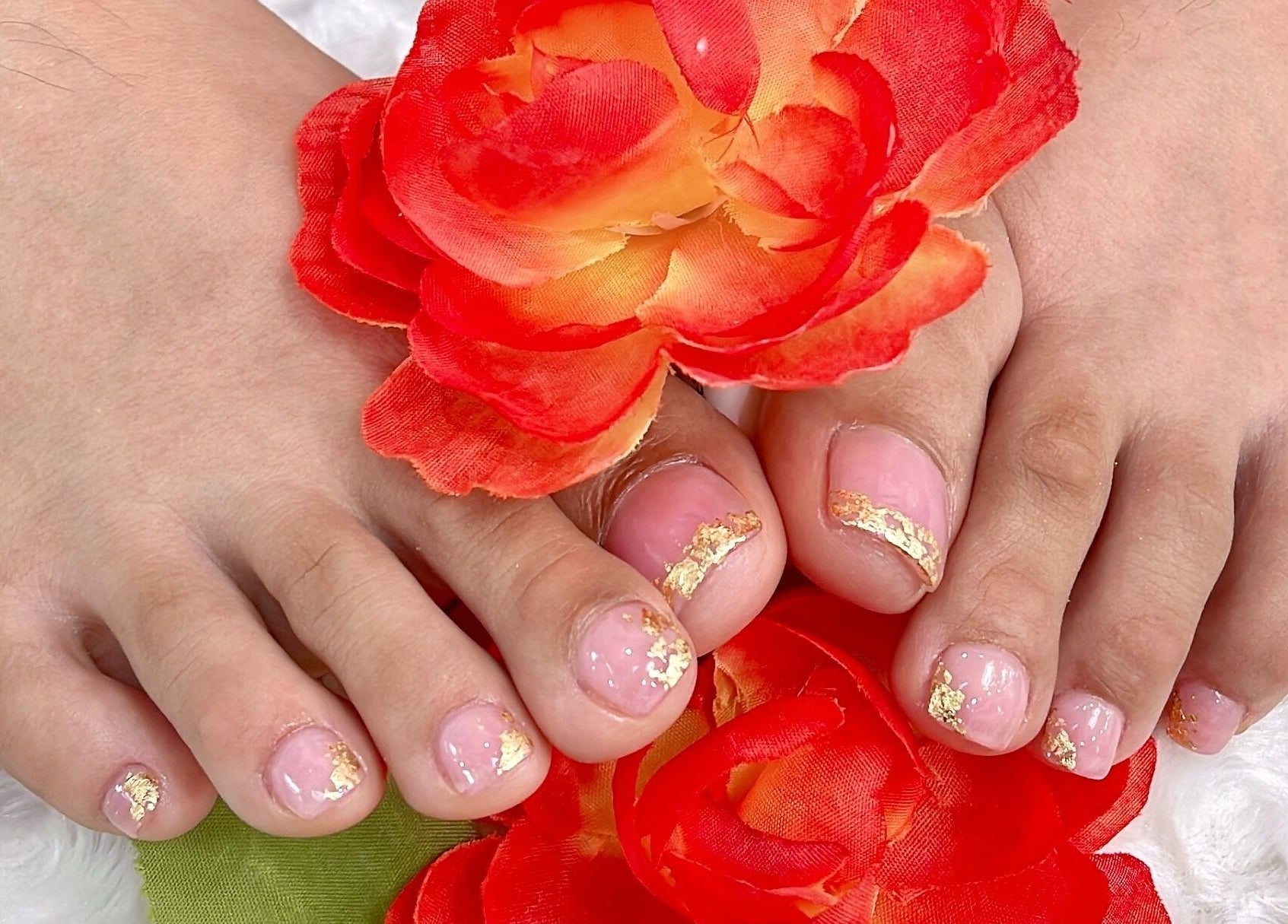 Elegant gold-accented pedicure at Iconic Nails Studio in Los Altos, California, US with vibrant red flowers.