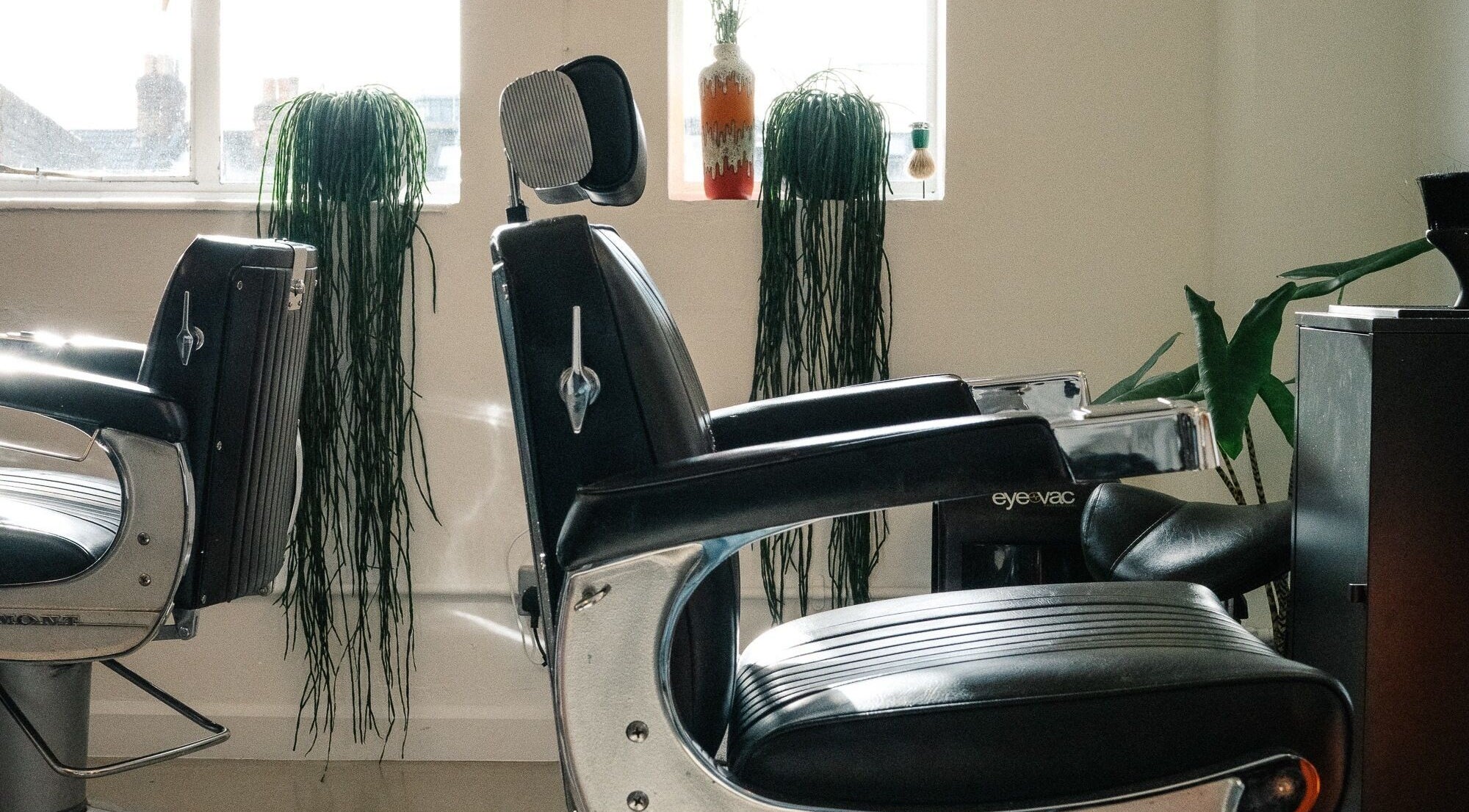 Elegant barber chairs at Lume Hair Studio | Netil Lane, London, England, GB. Natural light and greenery enhance the space.