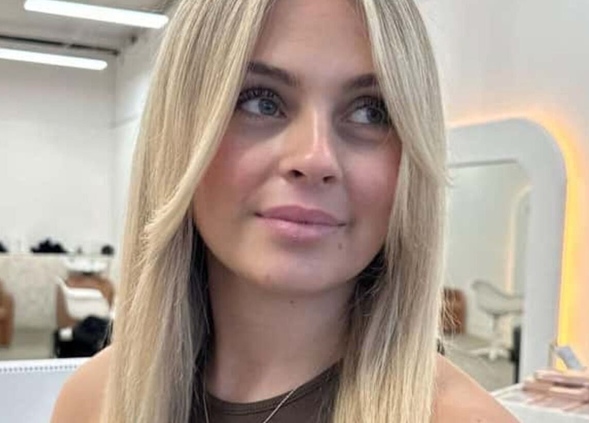 Woman with blonde hair smiling inside BIMBOS salon, Palm Beach, Queensland, AU.