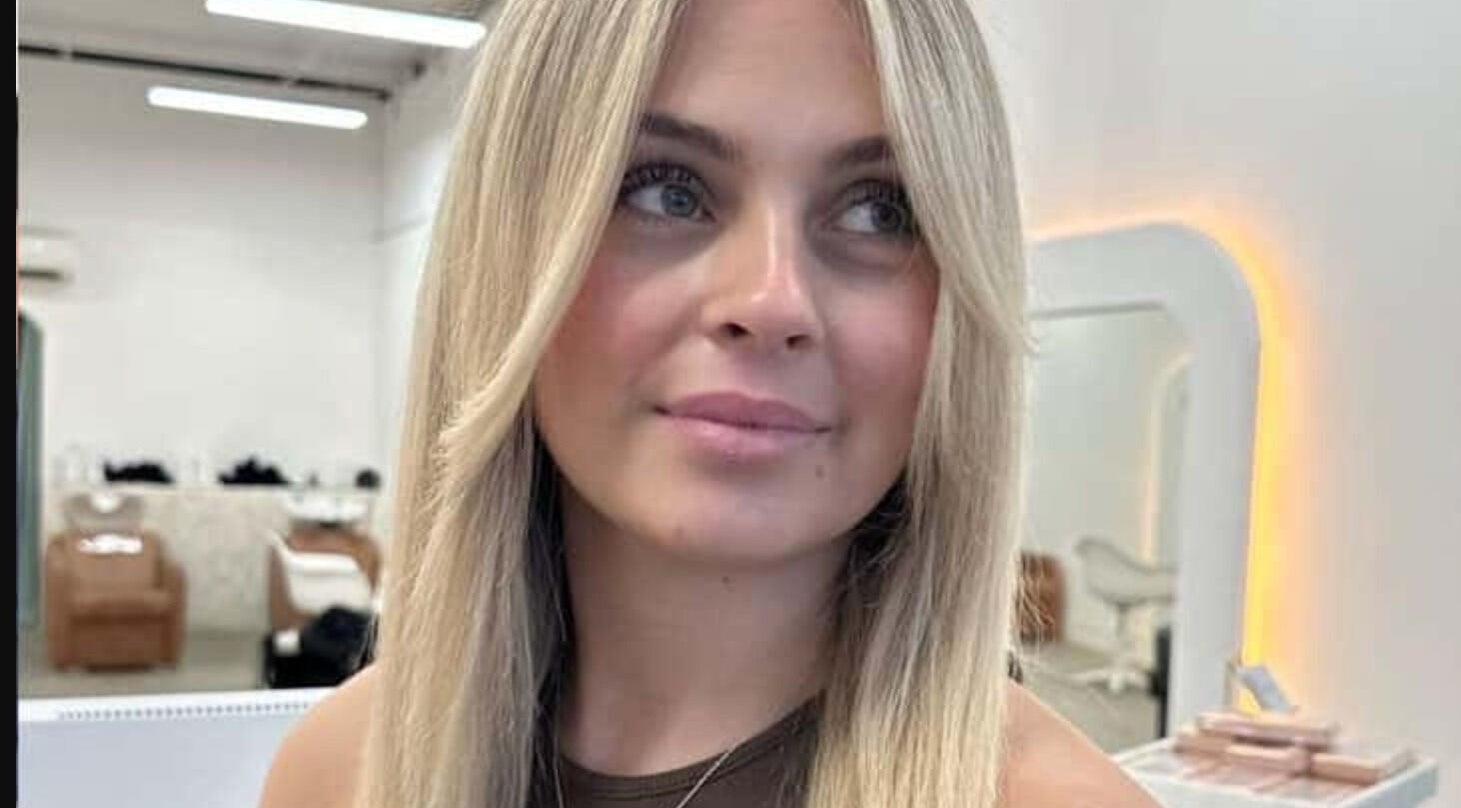 Woman with blonde hair smiling inside BIMBOS salon, Palm Beach, Queensland, AU.