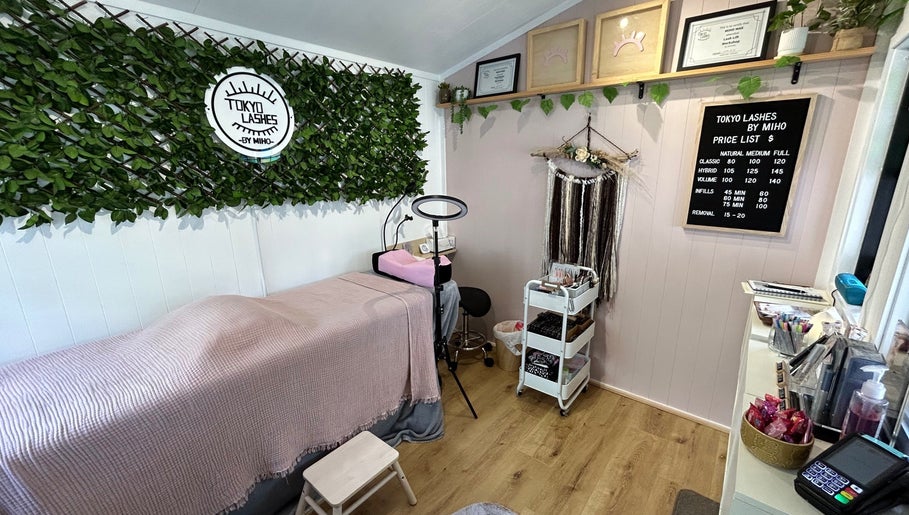Cozy interior of The Lash Hub in Auckland, NZ, featuring a treatment bed, lush decor, and beauty products.