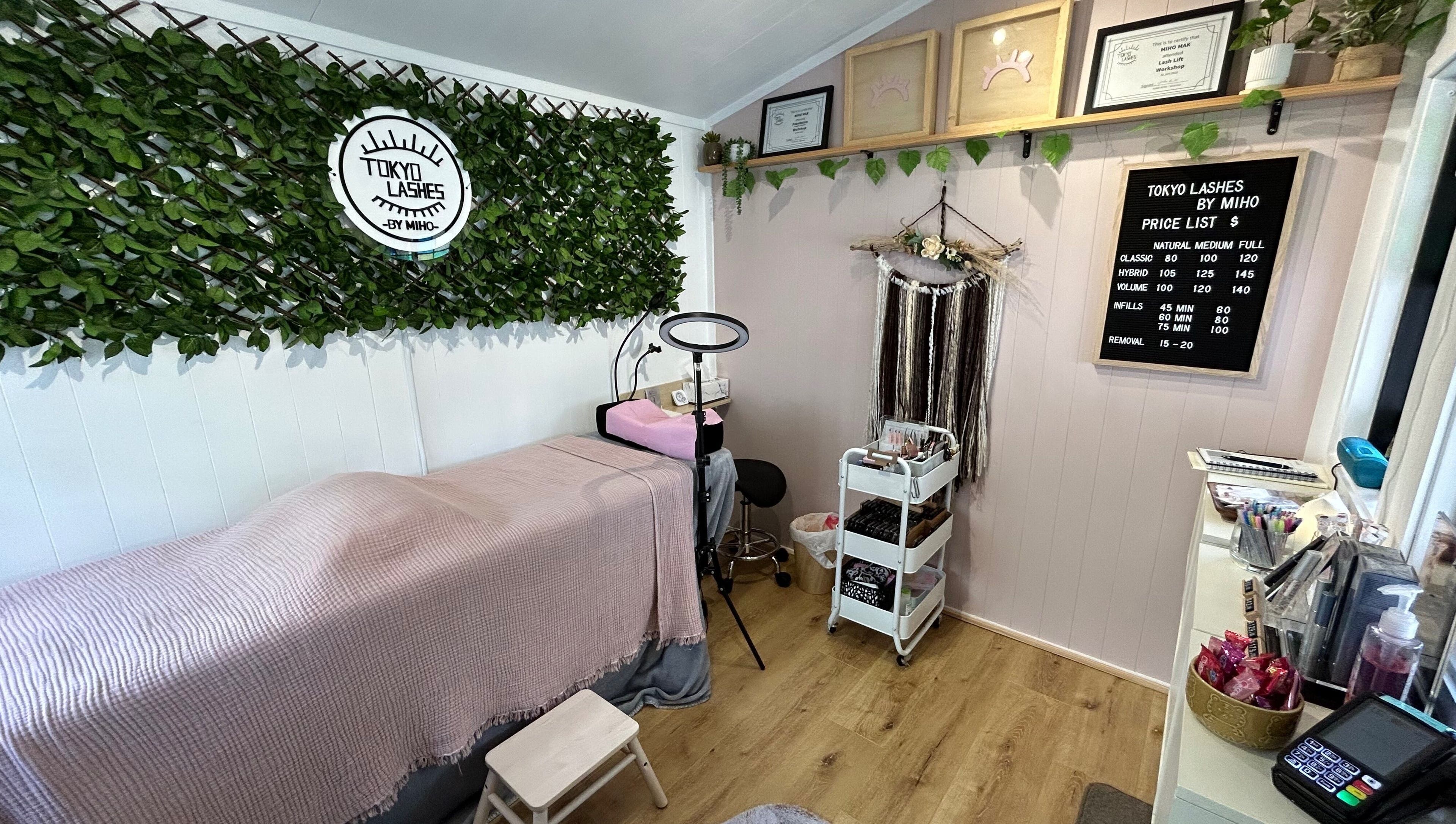 Cozy interior of The Lash Hub in Auckland, NZ, featuring a treatment bed, lush decor, and beauty products.