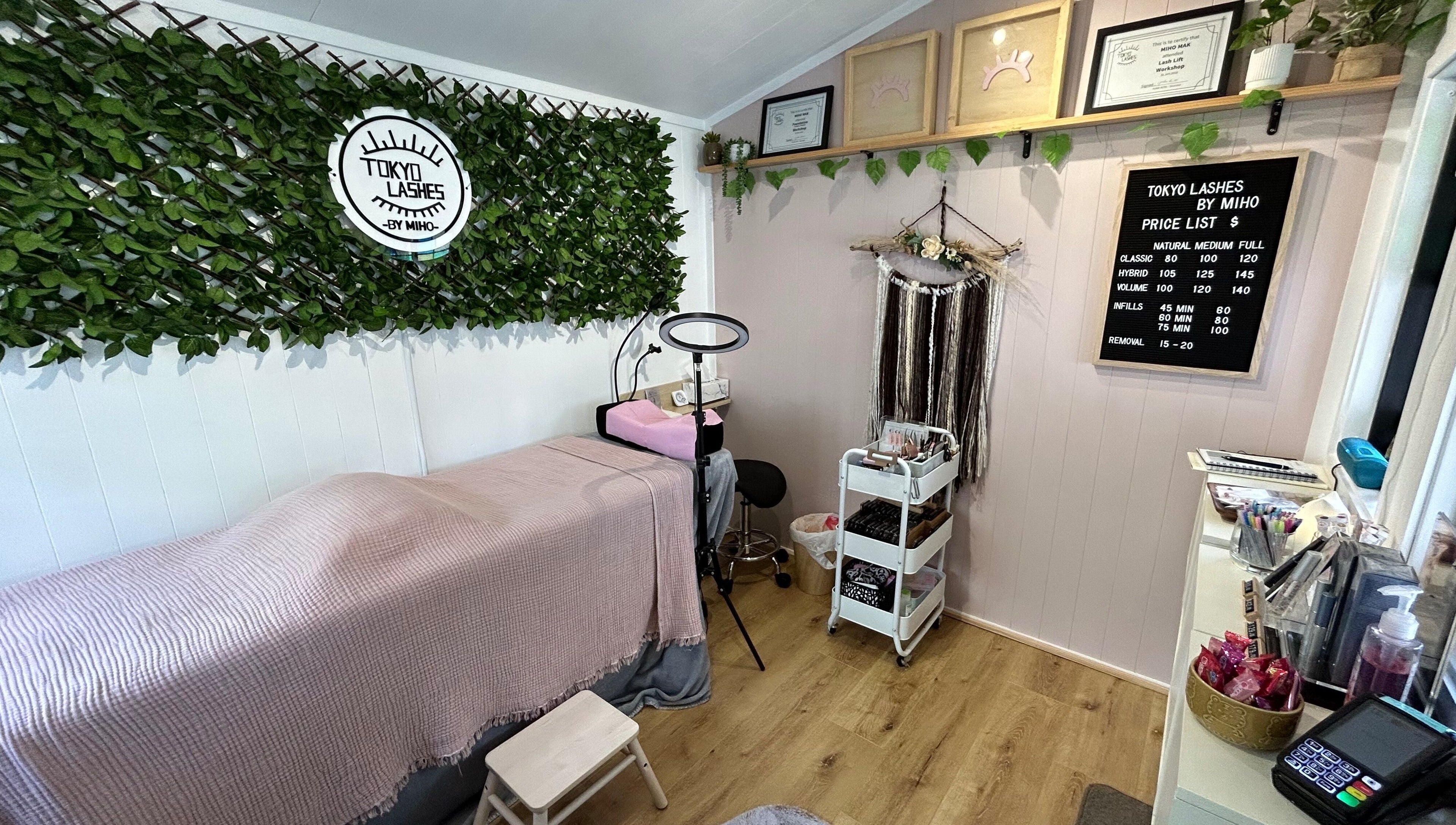 Cozy interior of The Lash Hub in Auckland, NZ, featuring a treatment bed, lush decor, and beauty products.