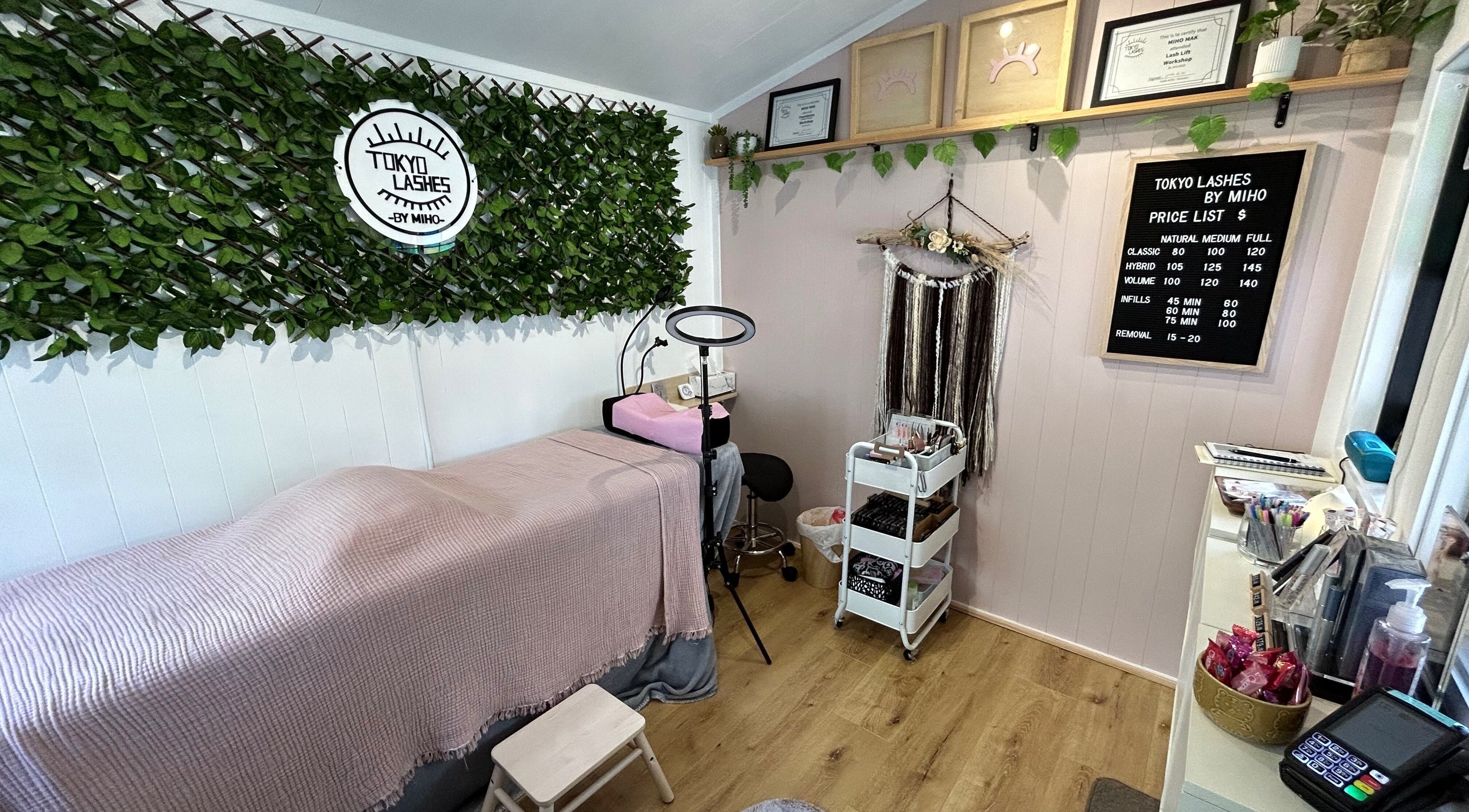 Cozy interior of The Lash Hub in Auckland, NZ, featuring a treatment bed, lush decor, and beauty products.