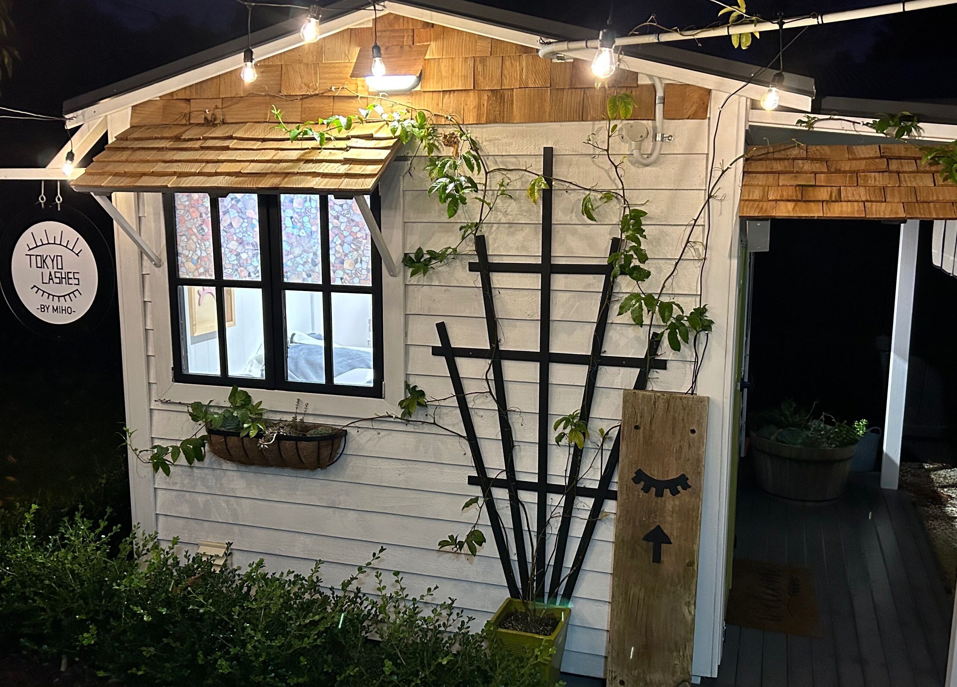 Charming exterior of The Lash Hub in Auckland, NZ, featuring inviting lights and greenery.