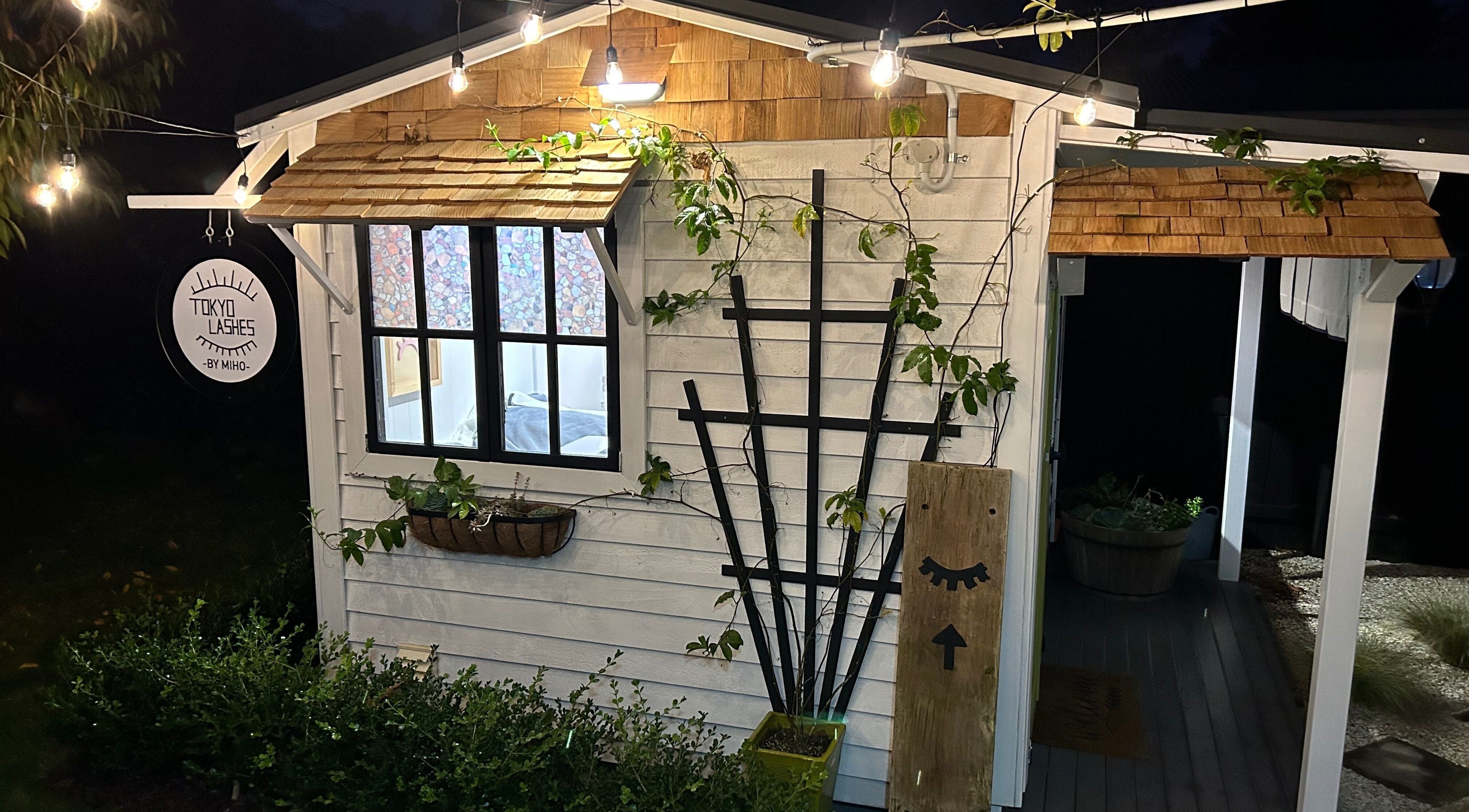 Charming exterior of The Lash Hub in Auckland, NZ, featuring inviting lights and greenery.