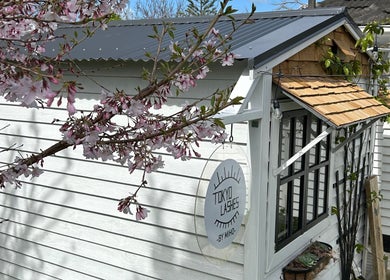 Charming exterior of The Lash Hub in Auckland, NZ with blooming cherry blossoms and rustic decor.
