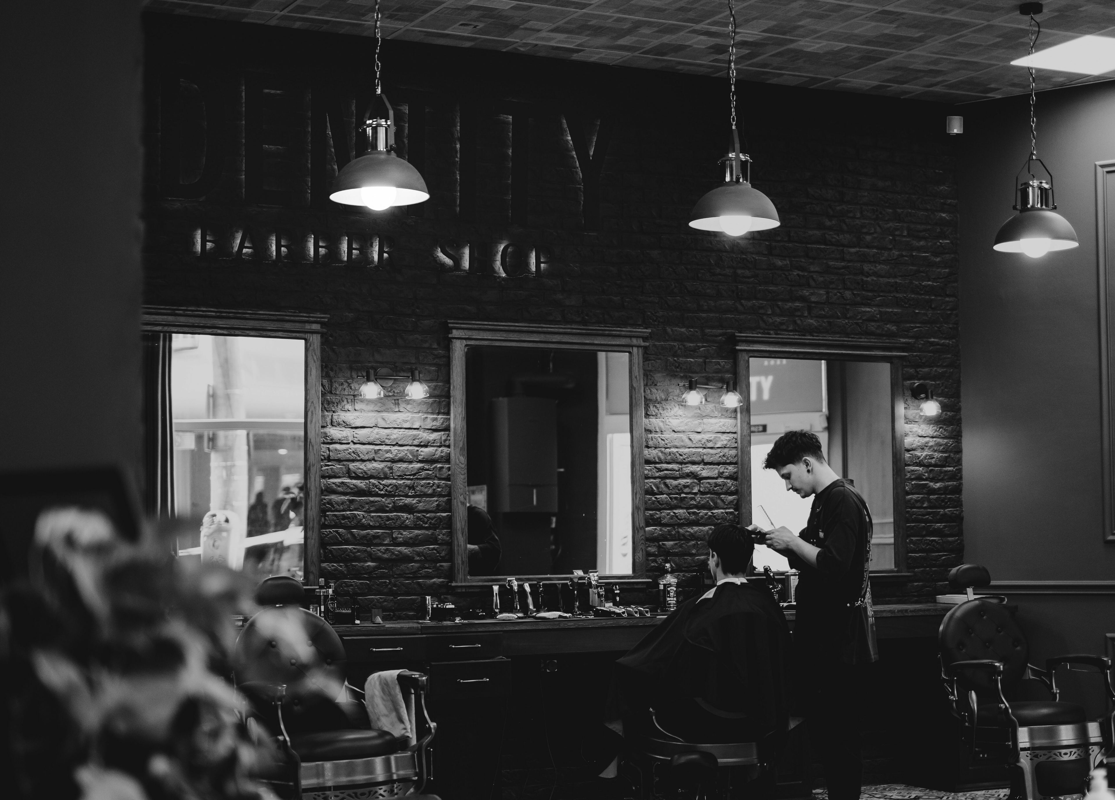Interiorul elegant al Identity Barber Shop din Cluj-Napoca, România, RO, în timp ce un frizer lucrează.
