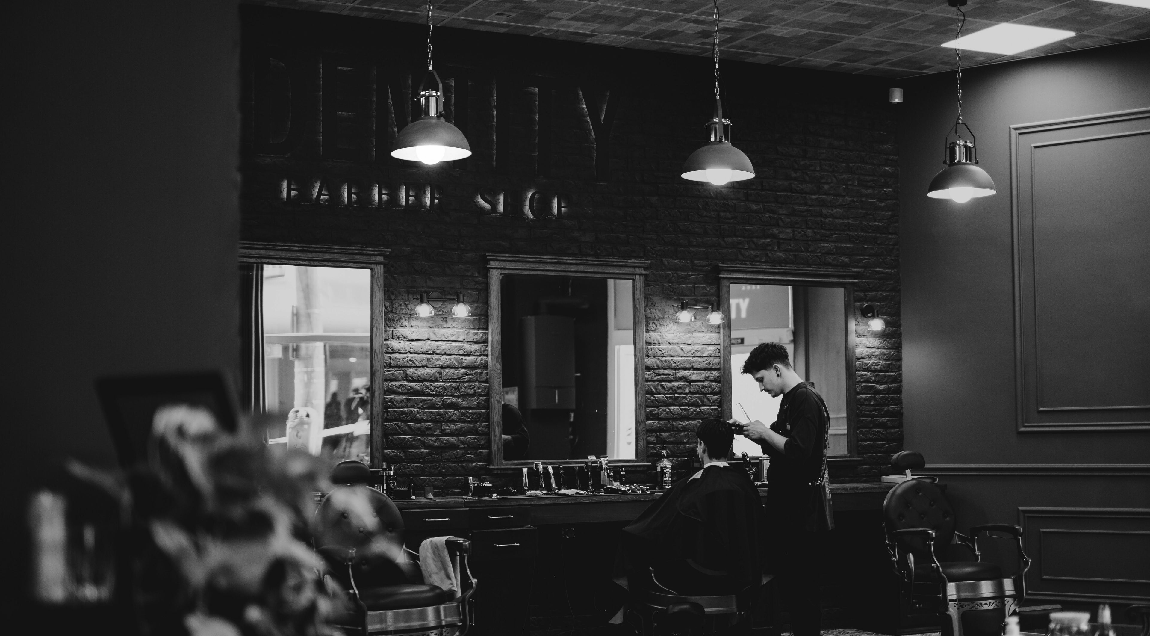 Interiorul elegant al Identity Barber Shop din Cluj-Napoca, România, RO, în timp ce un frizer lucrează.