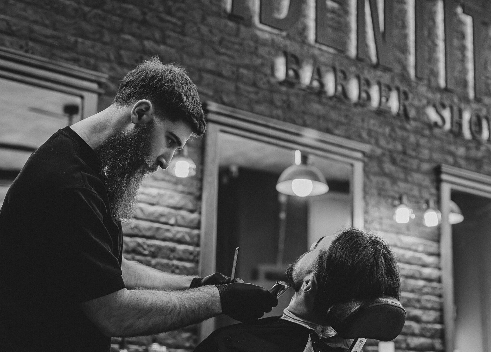Barber tundând un client la Identity Barber Shop, Cluj-Napoca, România, RO, într-un ambient elegant.