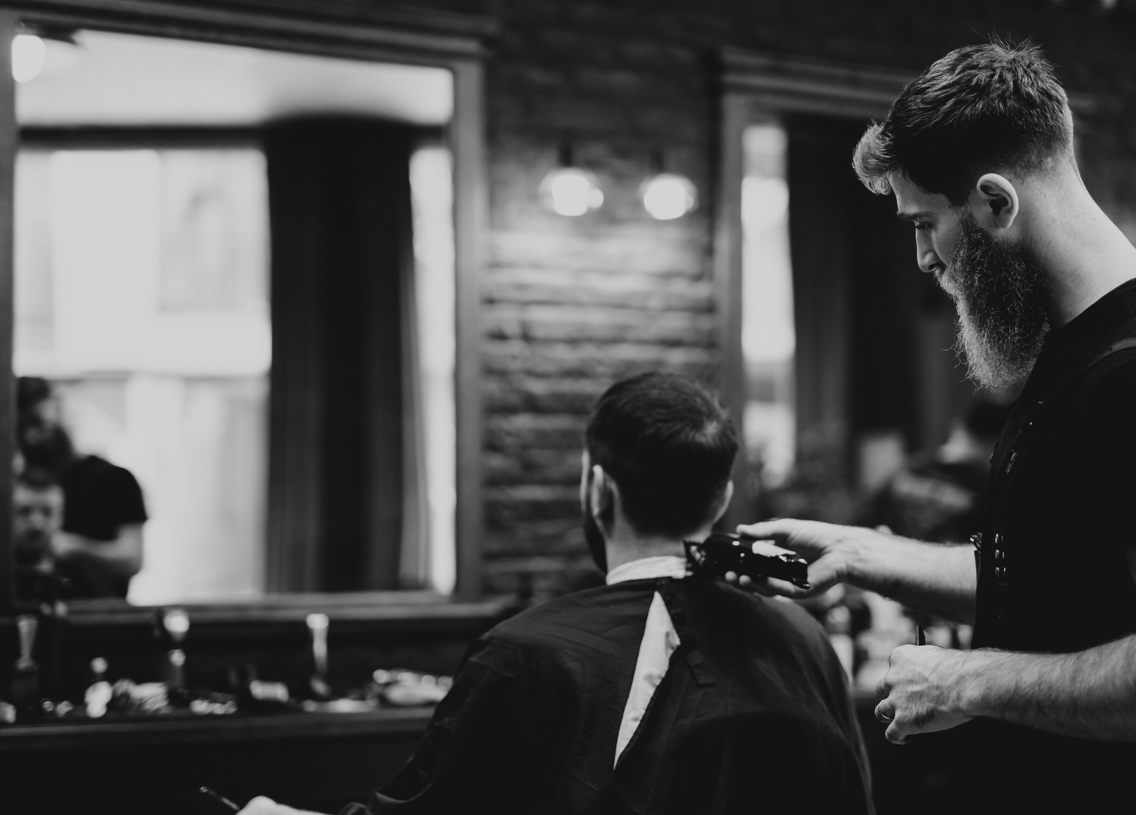 Frizer în acțiune la Identity Barber Shop, Cluj-Napoca, România, RO, creând un tuns modern și elegant.
