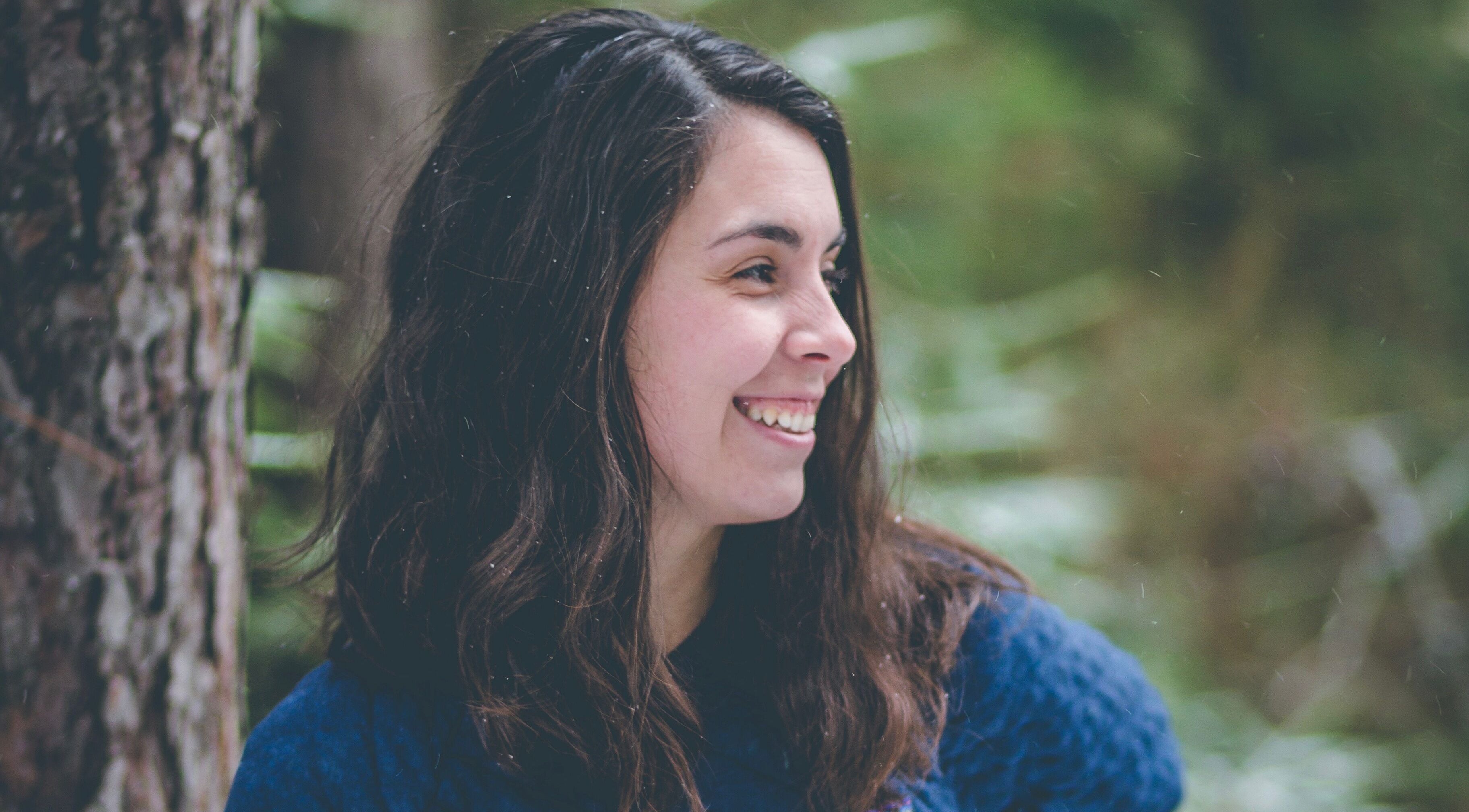 Femme souriante à MÉGANTIC Ostéopathie familiale, Lac-Mégantic, Québec, CA, entourée de nature verte.