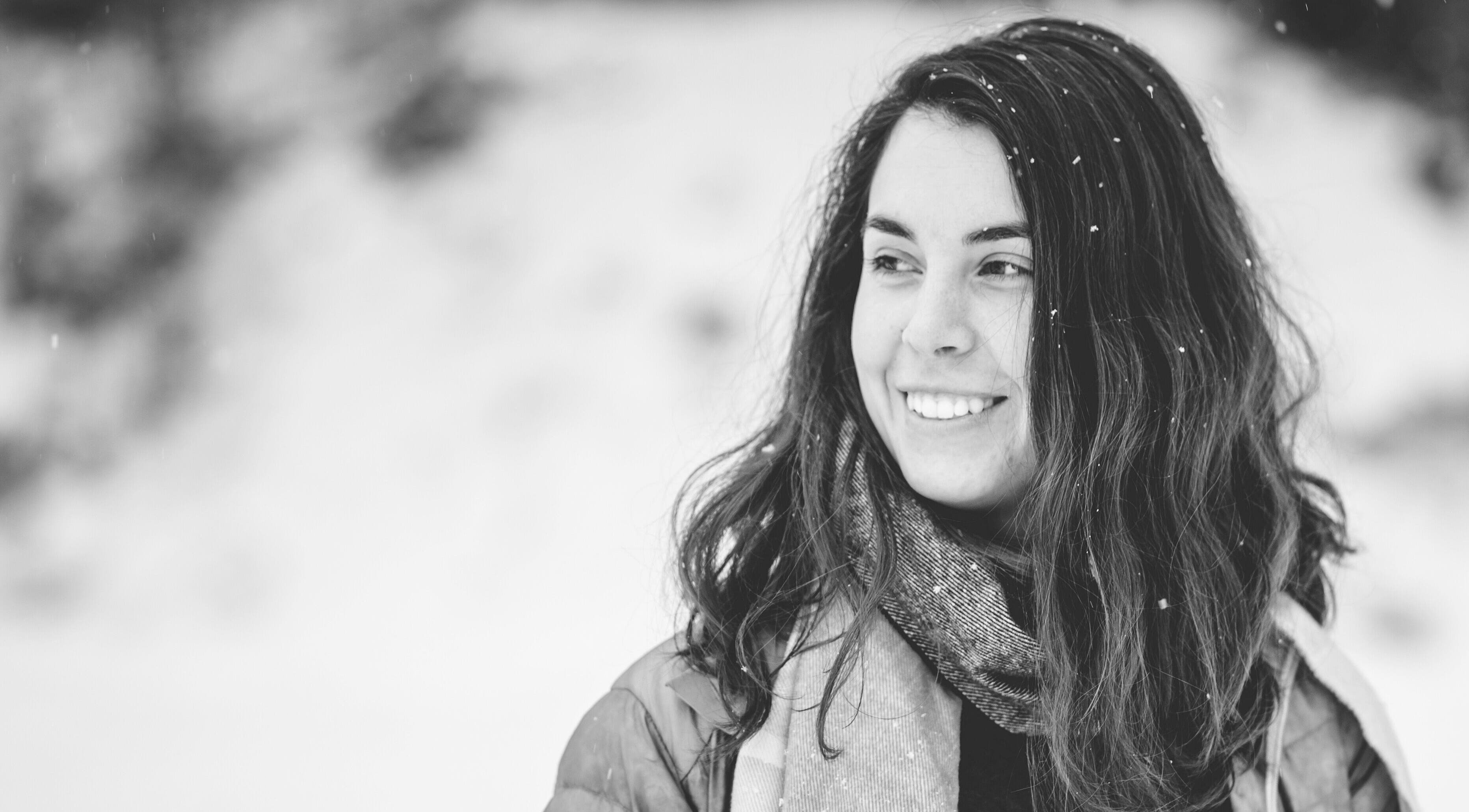 Portrait en noir et blanc d'une femme souriante devant la neige à MÉGANTIC Ostéopathie familiale, Lac-Mégantic, Québec, CA.