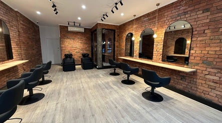 Modern salon interior at Hair by Coco Milk, Melbourne, Victoria, AU with stylish chairs and brick walls.