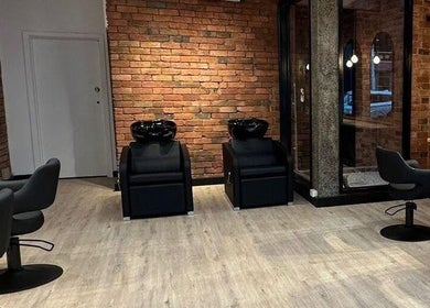 Modern salon interior at Hair by Coco Milk in Melbourne, Victoria, AU with sleek chairs and brick walls.