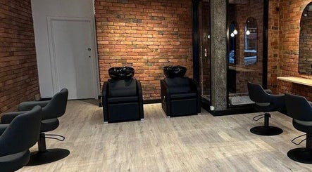 Modern salon interior at Hair by Coco Milk in Melbourne, Victoria, AU with sleek chairs and brick walls.