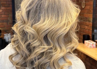 Blonde curls styled at Hair by Coco Milk, Melbourne, Victoria, AU. Elegant salon setting with brick walls.