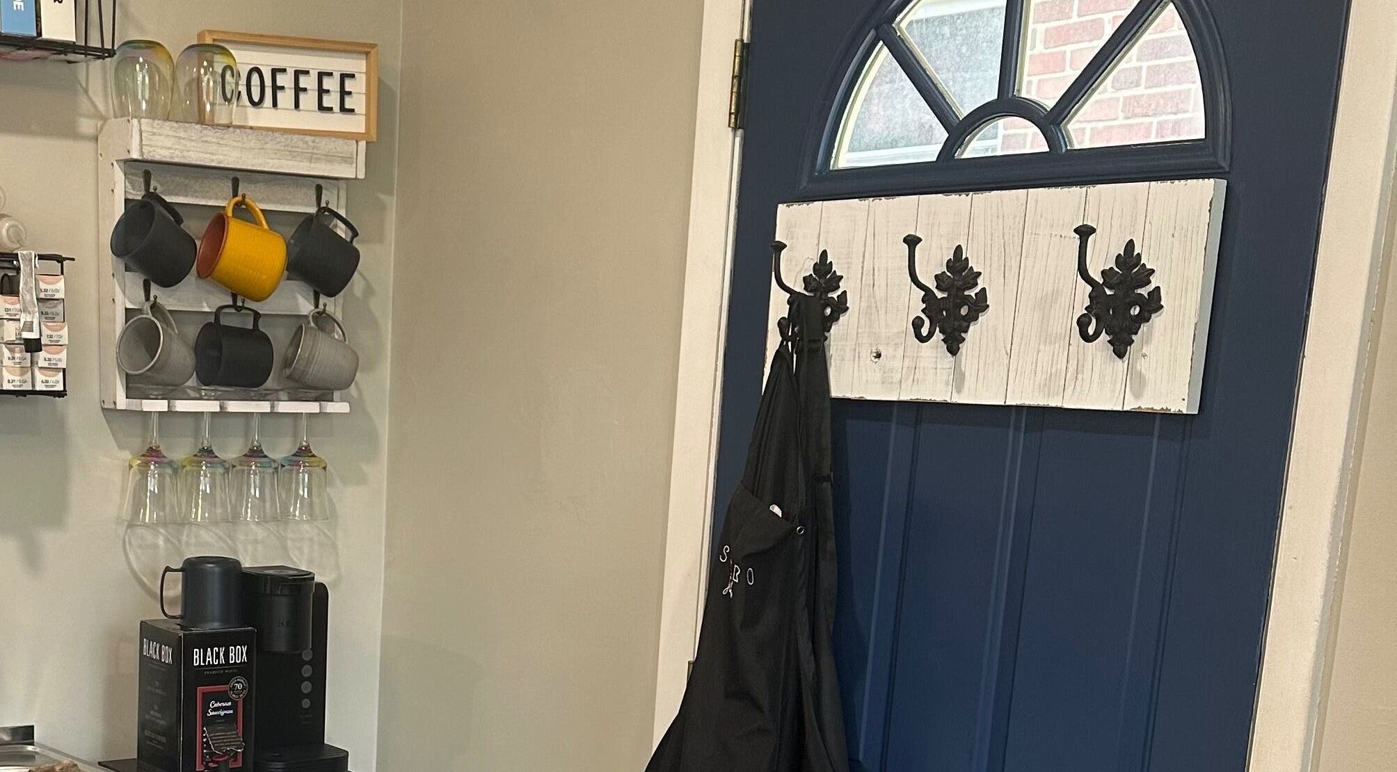 Cozy coffee corner in Sacro Studio, LLC, Bethlehem, Pennsylvania, US with mugs, a coffee machine, and decorative hooks.