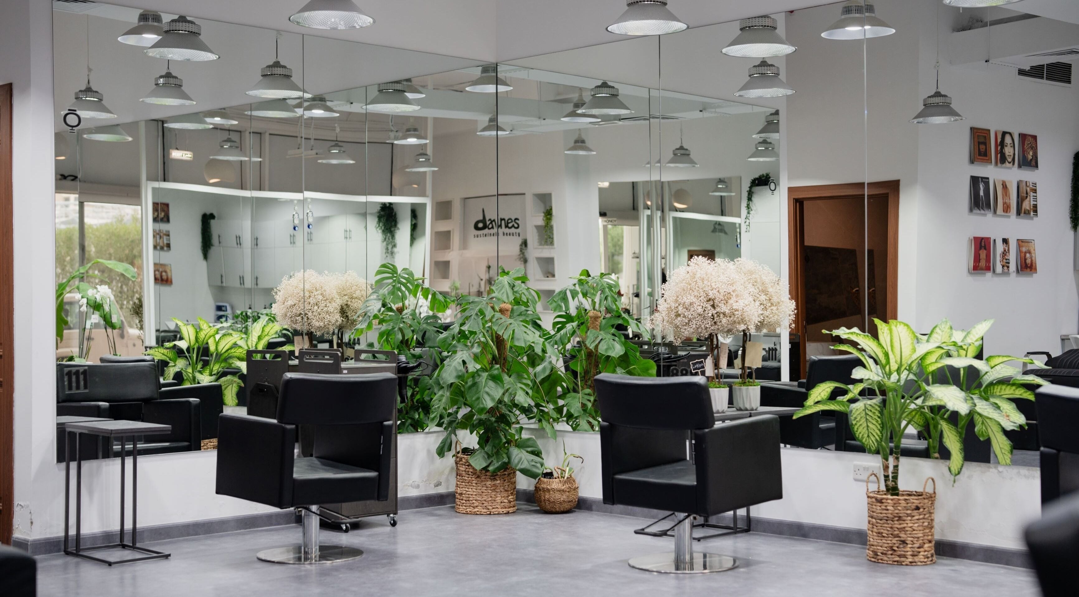 Modern interior of FRQNCY Hair Salon in Dubai, AE with elegant chairs and lush greenery.
