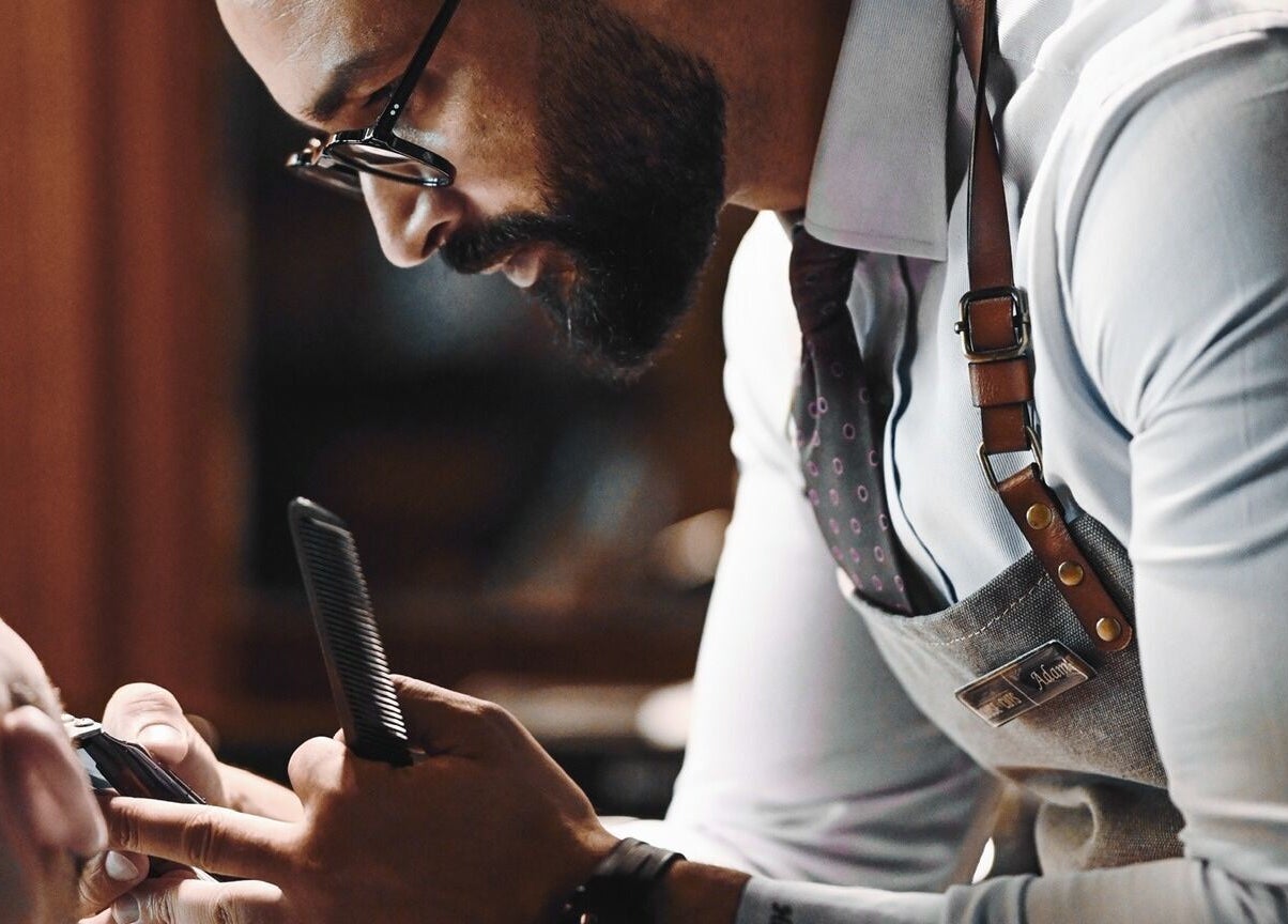 Barber offering a haircut at House of Cuts - Media City, Dubai, Dubai, AE. Experience expert grooming services.