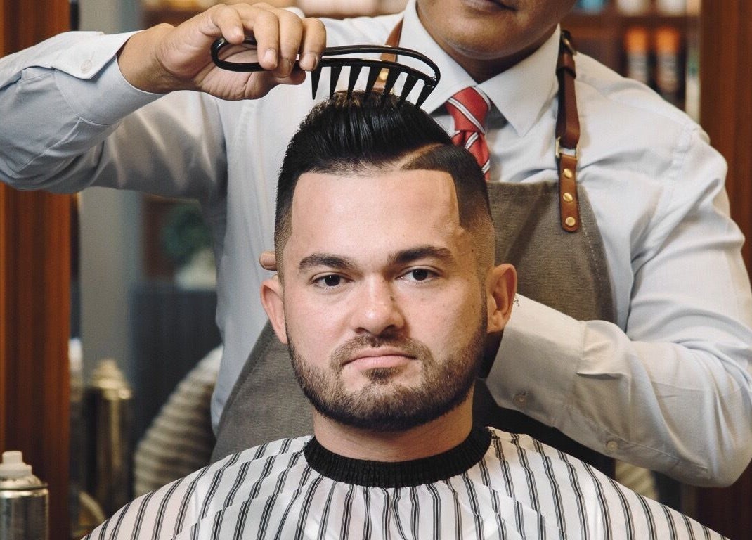 Barber styling hair at House of Cuts - Media City, Dubai, Dubai, AE promoting professional grooming.