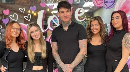 Team of stylists at Rehab Hair Salon in Allesley, Park, England, GB, smiling in front of a heart-decorated window.