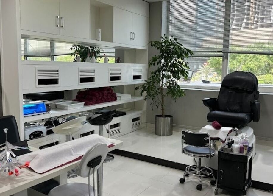 Bright nail salon area at Crystal Beauty Lounge, Dubai, AE, featuring manicure stations and a massage chair.