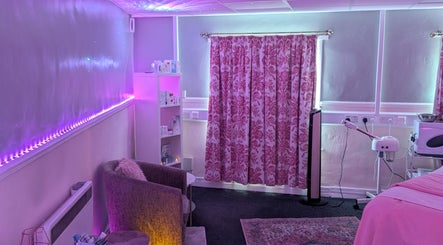 Elegant treatment room at Skinfit Studio, Shifnal, England, GB, featuring soothing pink lighting and floral decor.
