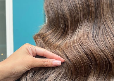 Hand touches silky brown waves at VP Hair Art Co Sutton, Birmingham, England, GB.