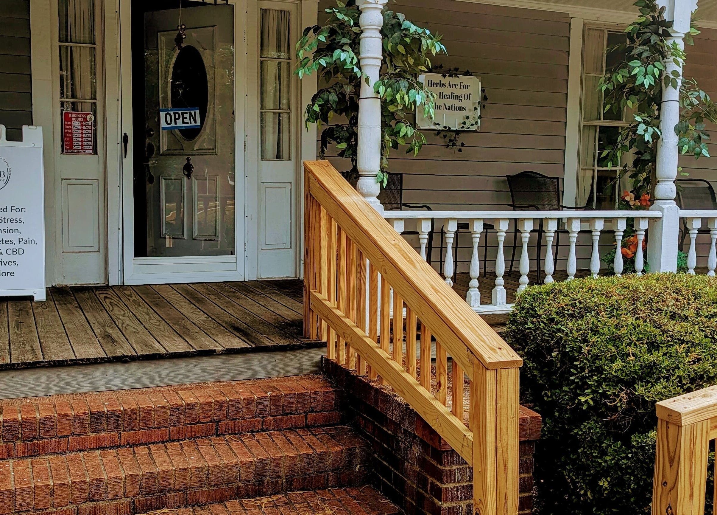 Inviting front porch of Arlana Styles Manextensions (ASME) in Latta, South Carolina, US, with open sign and herbal display.