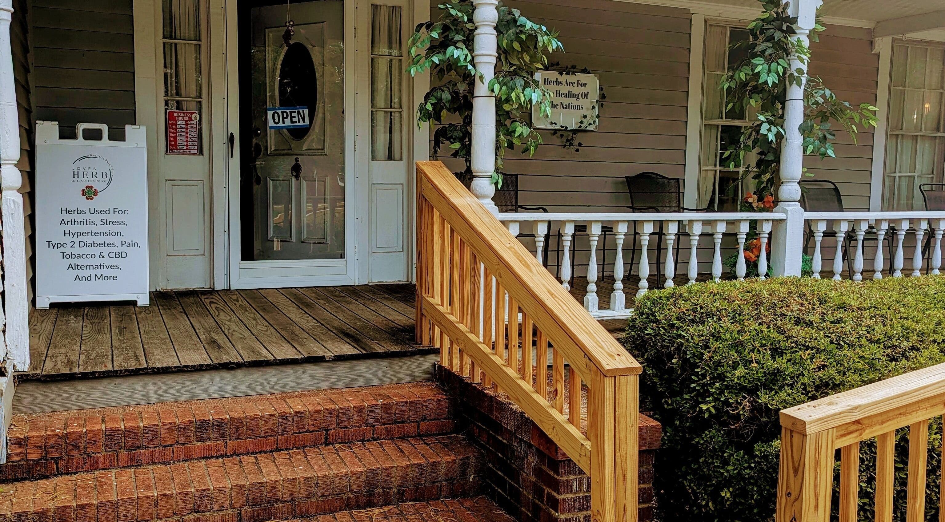Inviting front porch of Arlana Styles Manextensions (ASME) in Latta, South Carolina, US, with open sign and herbal display.